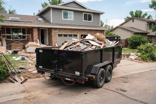 Industrial junk removal trailer loaded with construction debris on a residential driveway.